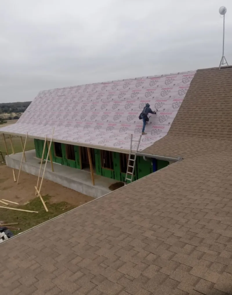 Worker preparing underlayment for a metal roof installation in Luzerne